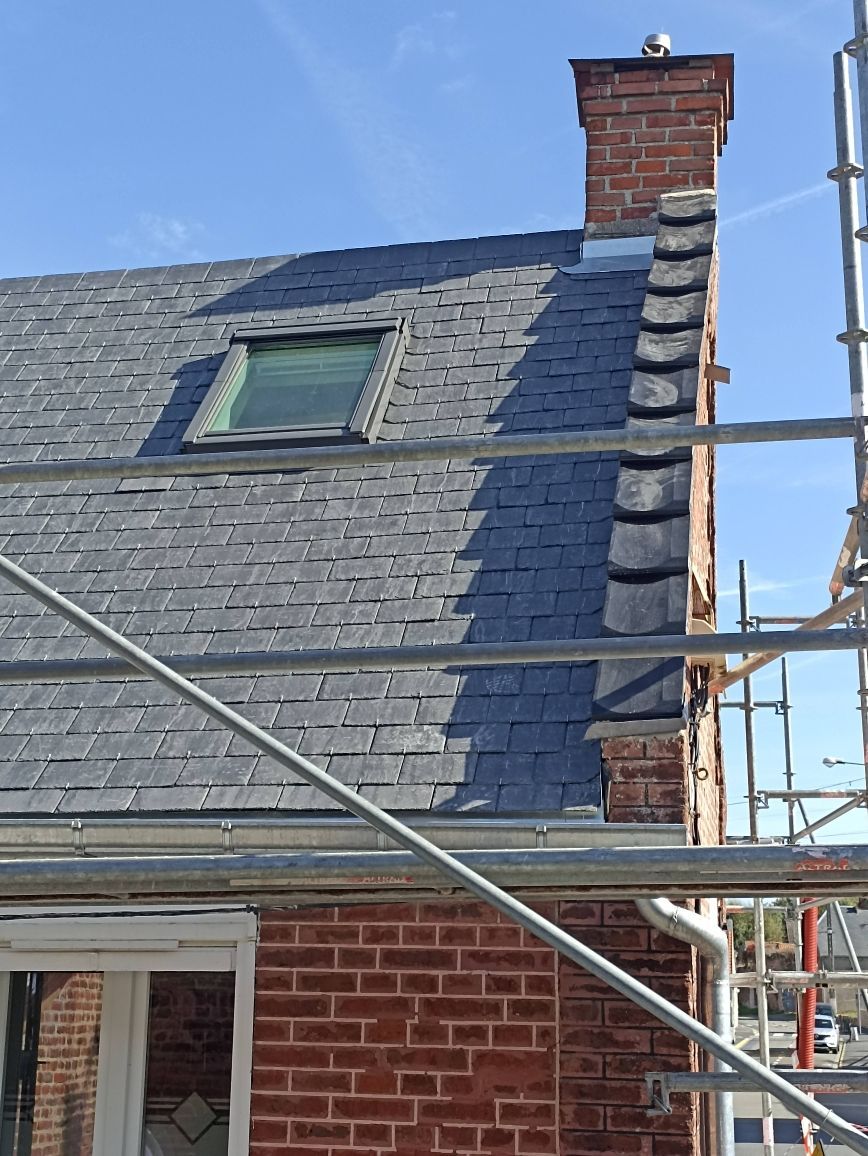 Maison en briques avec toit en ardoises, lucarne, cheminée et échafaudage le long du mur latéral