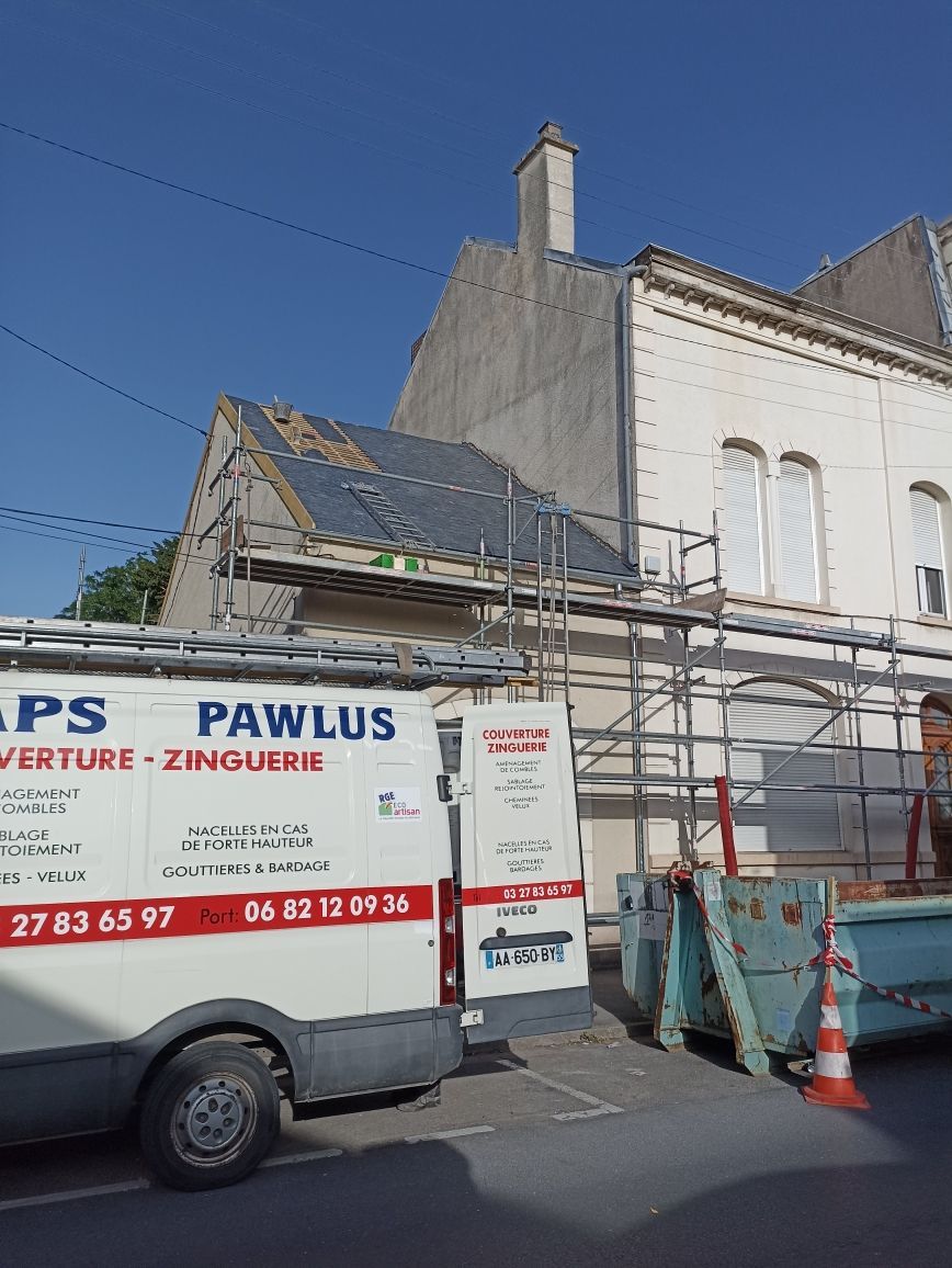 Façade d'un immeuble avec échafaudages, à côté d'une camionnette utilitaire Pawlus et de cônes de signalisation