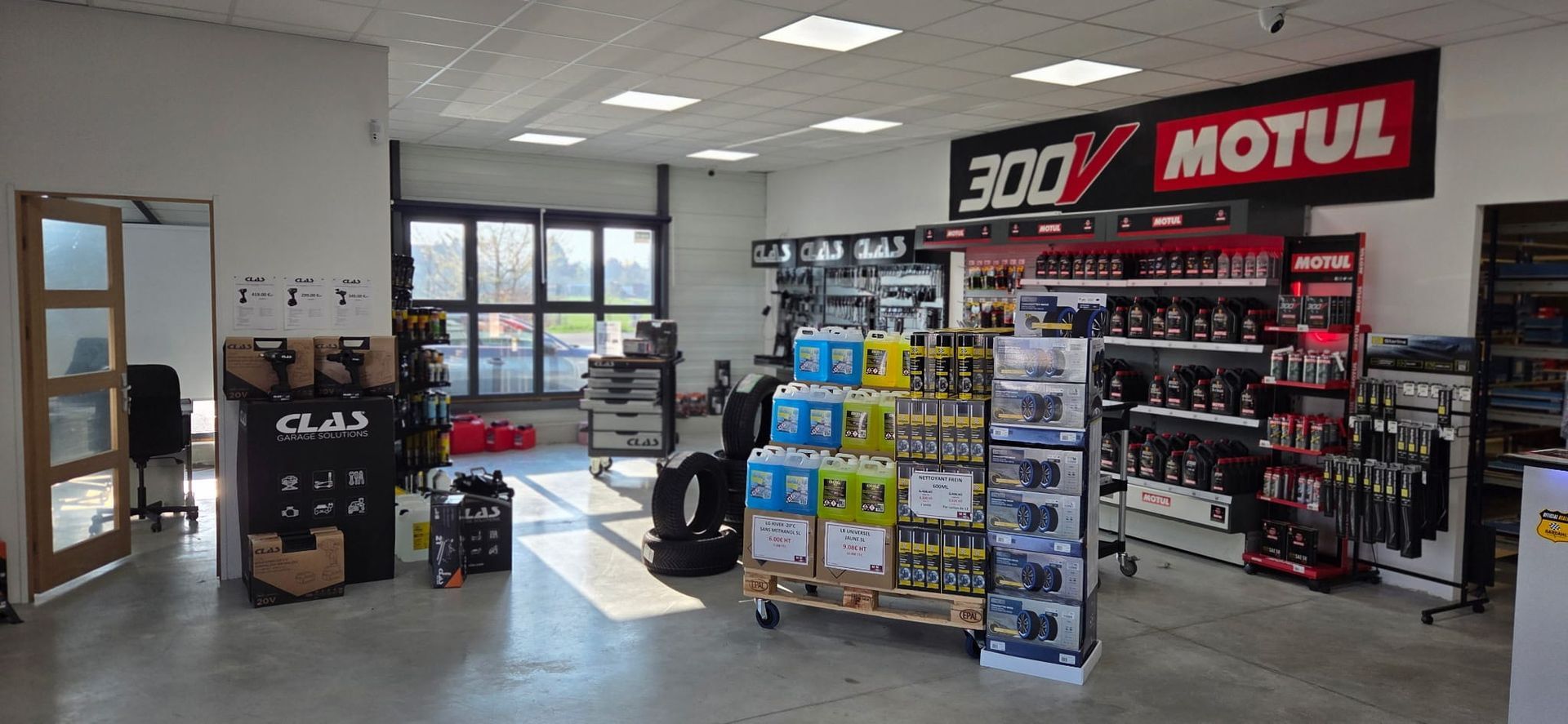 Un magasin de pièces automobiles lumineux et spacieux avec des allées remplies de fournitures.