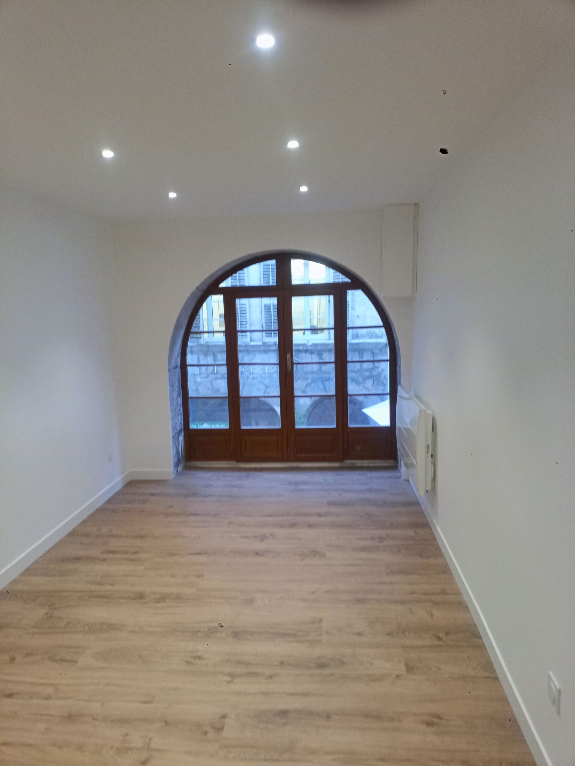 Pièce intérieure rénovée avec murs blancs et sol effet bois