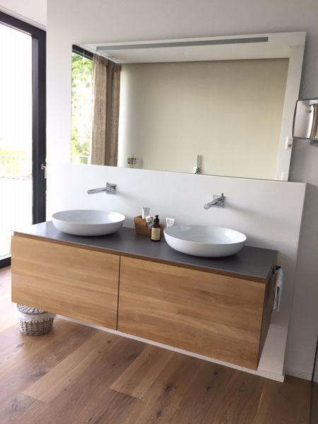 Moderner Badezimmer-Waschtisch mit Doppelwaschbecken, Holzschrank, grossem Spiegel und Holzboden.