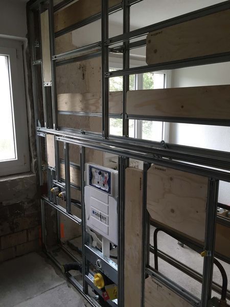Metallwandkonstruktion und freiliegende Rohrleitungen in einem unfertigen Raum mit Fenster.