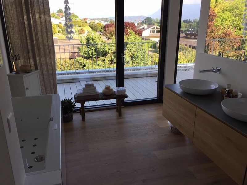 Moderne Küche mit Holzboden, grossen Glastüren und einer Spüle mit Blick in den Garten