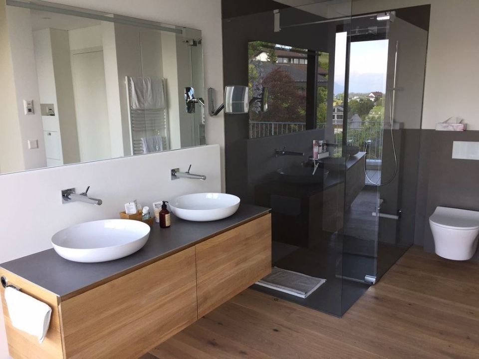 Modernes Badezimmer mit Doppelwaschbecken, Waschtisch aus Holz, grossem Spiegel und Duschkabine aus Glas