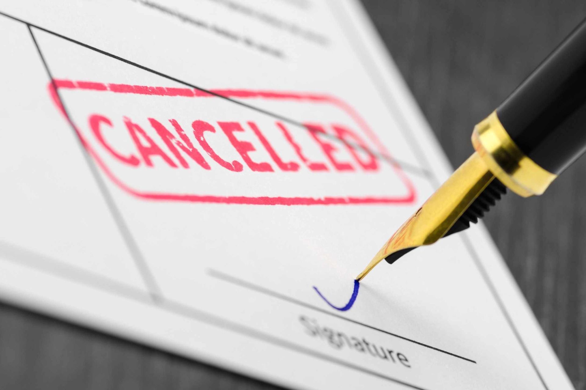 Una pluma estilográfica está firmando un documento que tiene la palabra cancelado estampada en él.