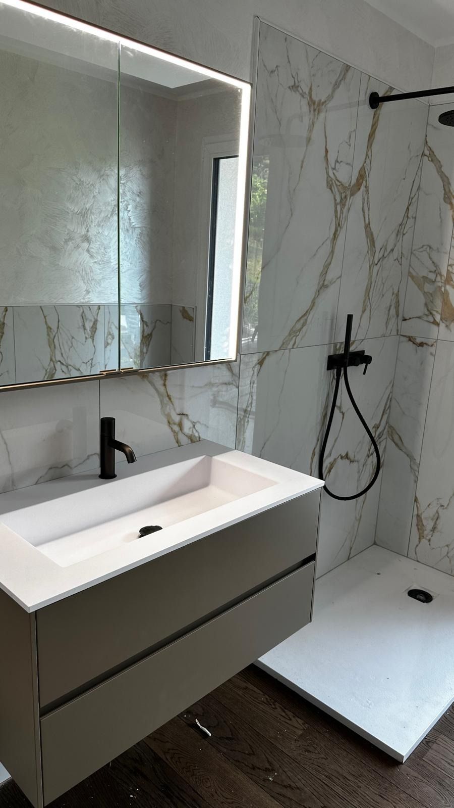 Bagno moderno con doccia in vetro, mobile lavabo sospeso, WC e grande specchio.