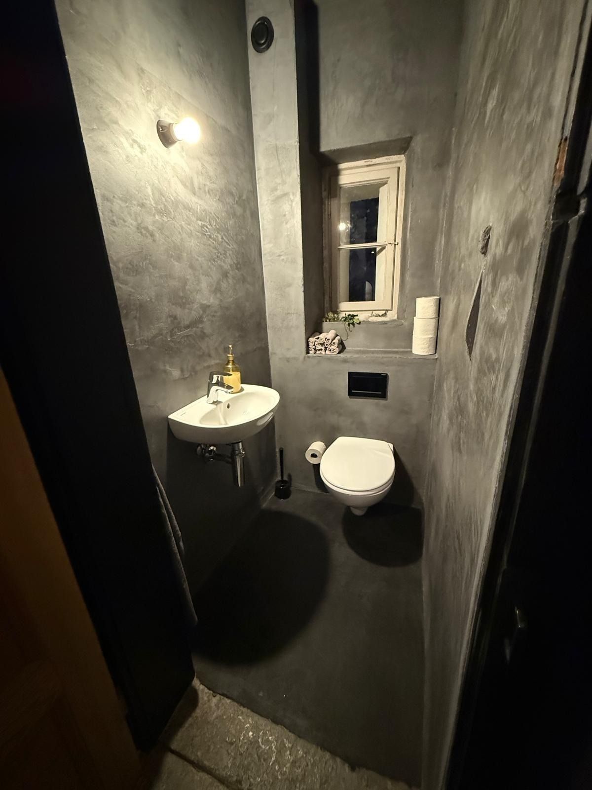 Tecnico in tuta blu che ripara un condizionatore d'aria, tenendo una cassetta degli attrezzi su una scala in un ambiente interno.