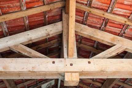 Charpente en bois sous des tuiles en terre cuite rouge à l'intérieur d'un plafond de grenier