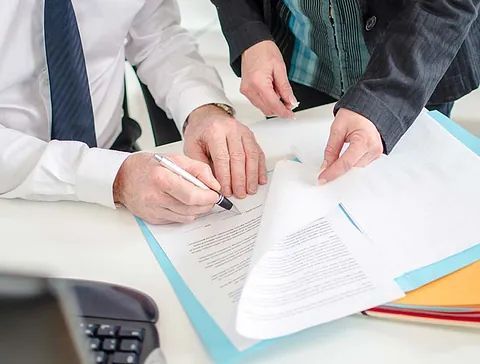 Un hombre y una mujer están sentados en una mesa firmando un documento.