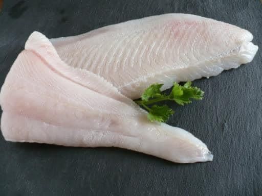 Zwei Fischstücke liegen auf einer Schieferplatte.