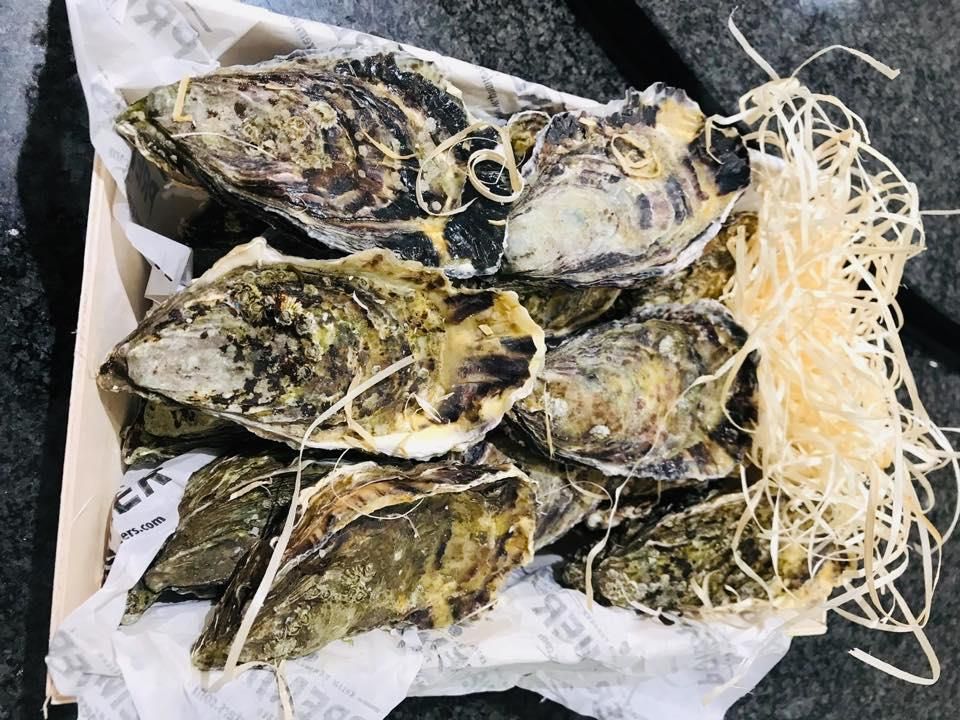 Eine Kiste gefüllt mit Austern und Stroh auf einem Tisch.