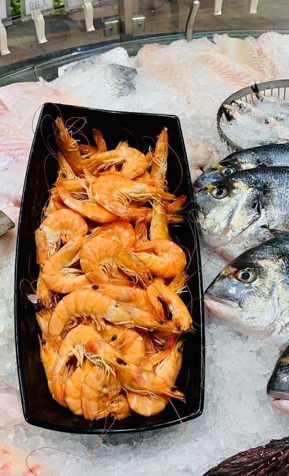 Eine Schüssel Garnelen steht neben Fisch auf Eis.