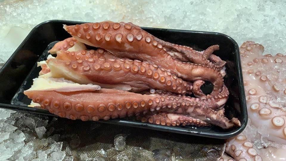 Ein schwarzes Tablett voller Oktopus steht auf Eis.