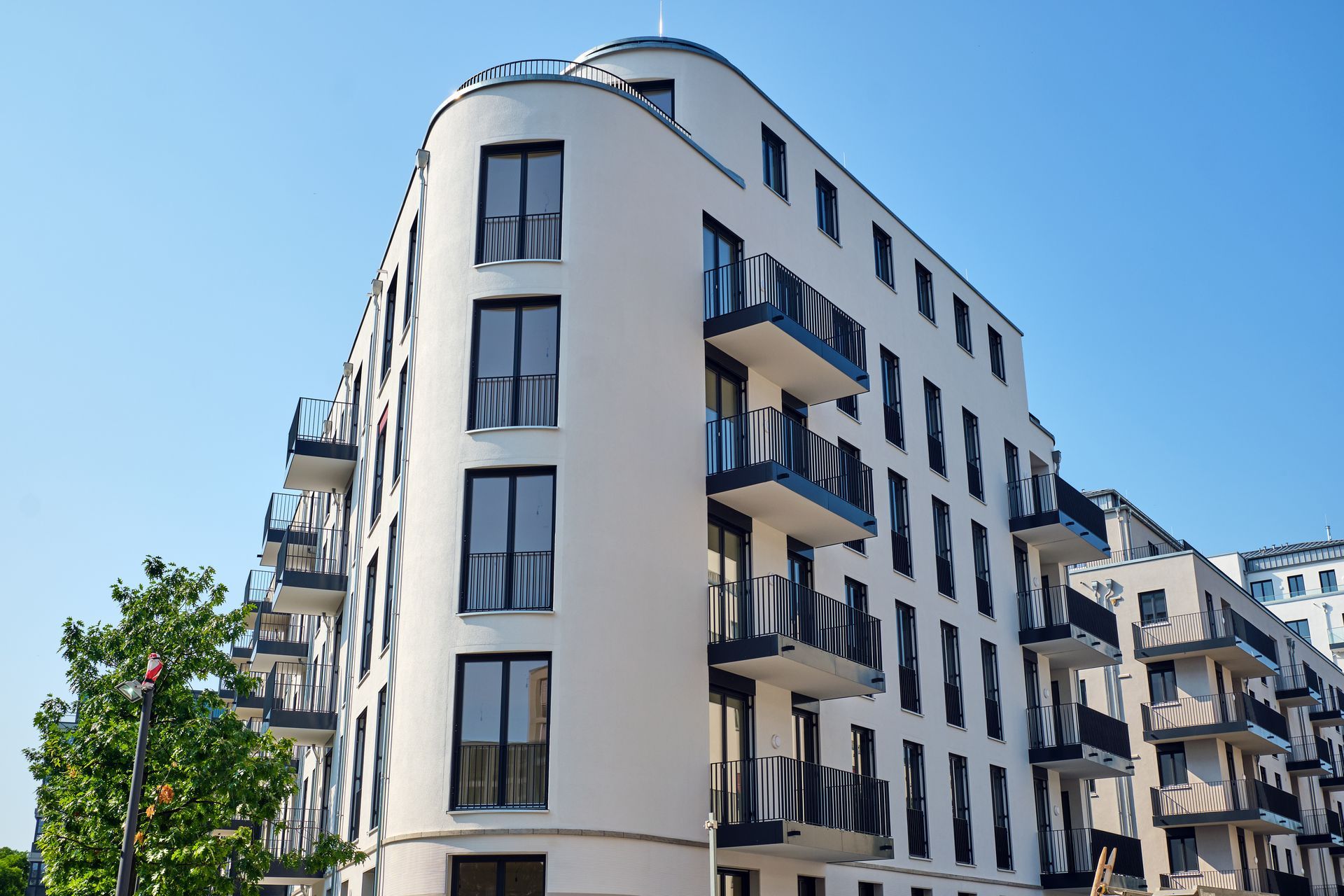 Immeuble d'appartements blanc moderne avec balcons sous un ciel bleu clair.
