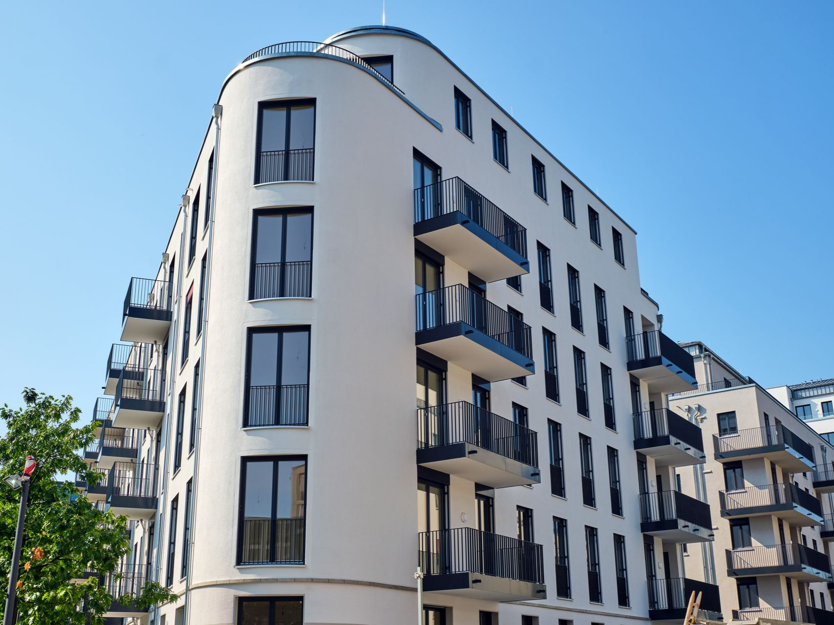 Immeubles d'appartements modernes blancs avec balcons sous un ciel bleu clair.