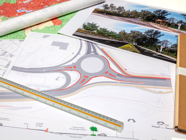 Plan architectural avec un rond-point, une règle et des photos de référence du paysage imprimées.