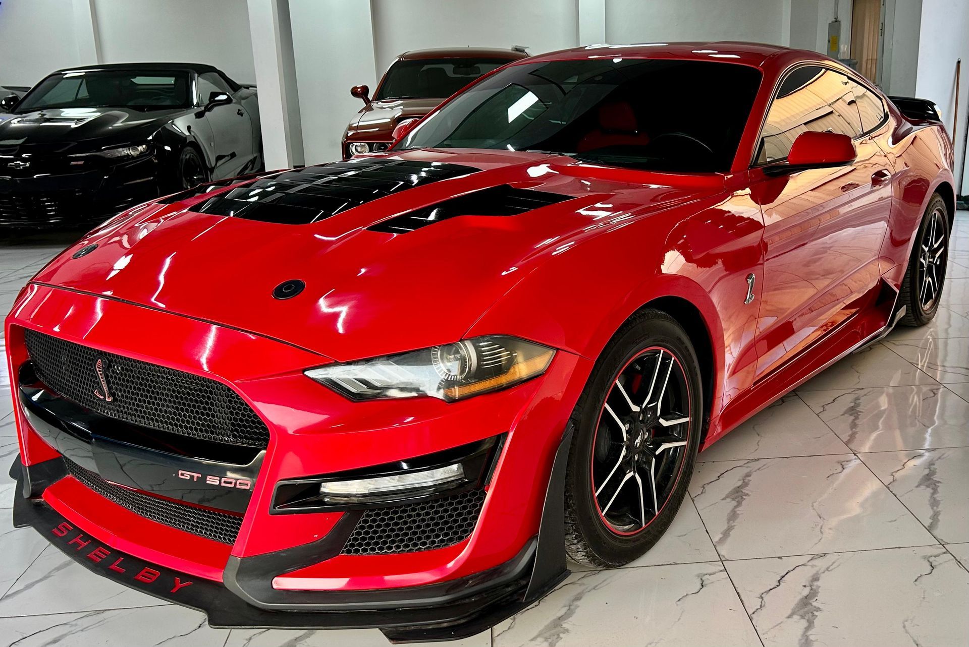 Un Ford Mustang rojo está estacionado en una sala de exposición.