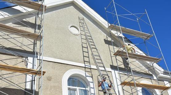 Un hombre está de pie en una escalera al costado de un edificio.