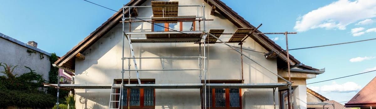Se está pintando una casa con andamios alrededor.