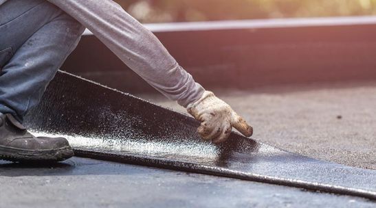 Un hombre está aplicando una capa de pintura a un techo.