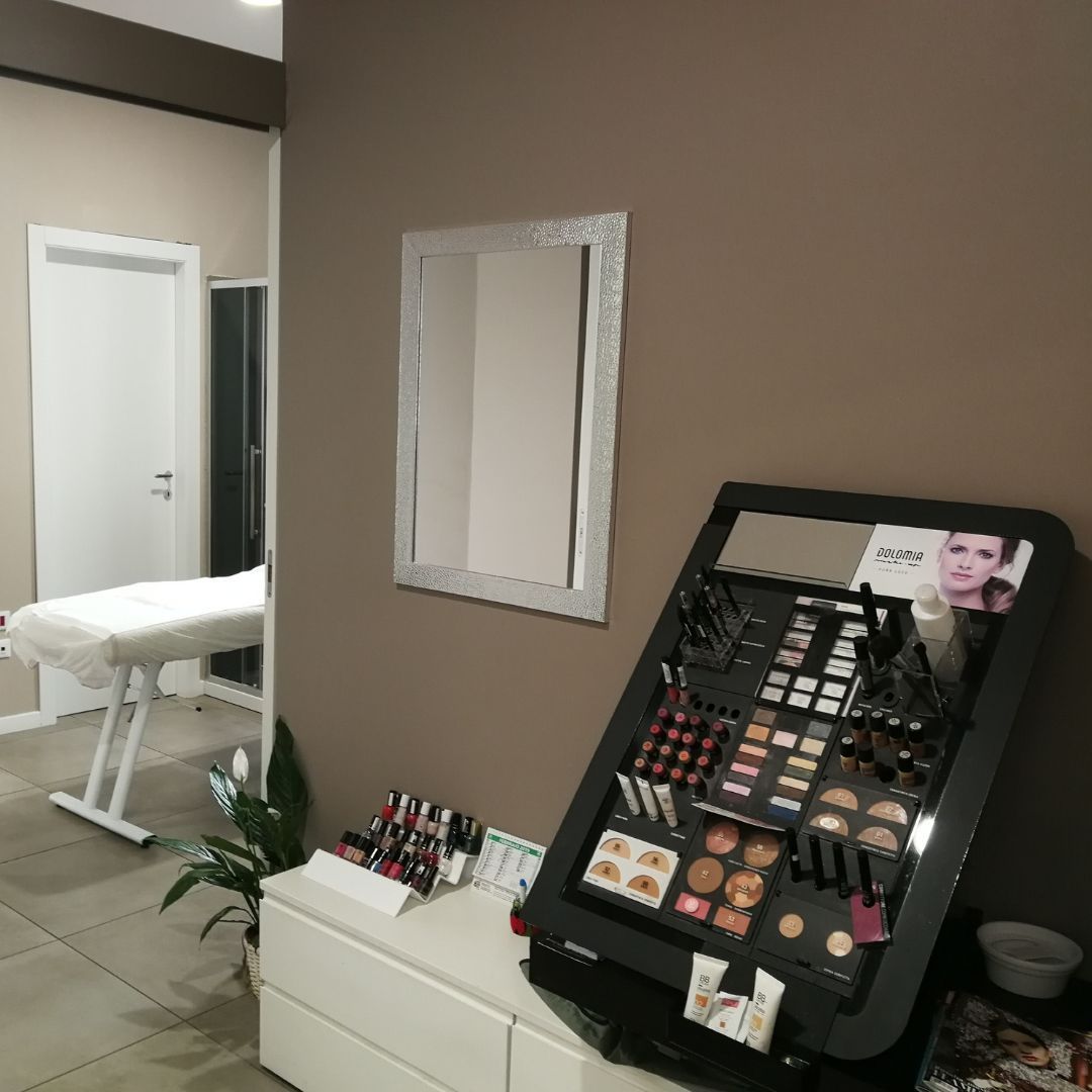 Espositore per il trucco vicino allo specchio in un salone di bellezza, che mostra vari prodotti cosmetici.