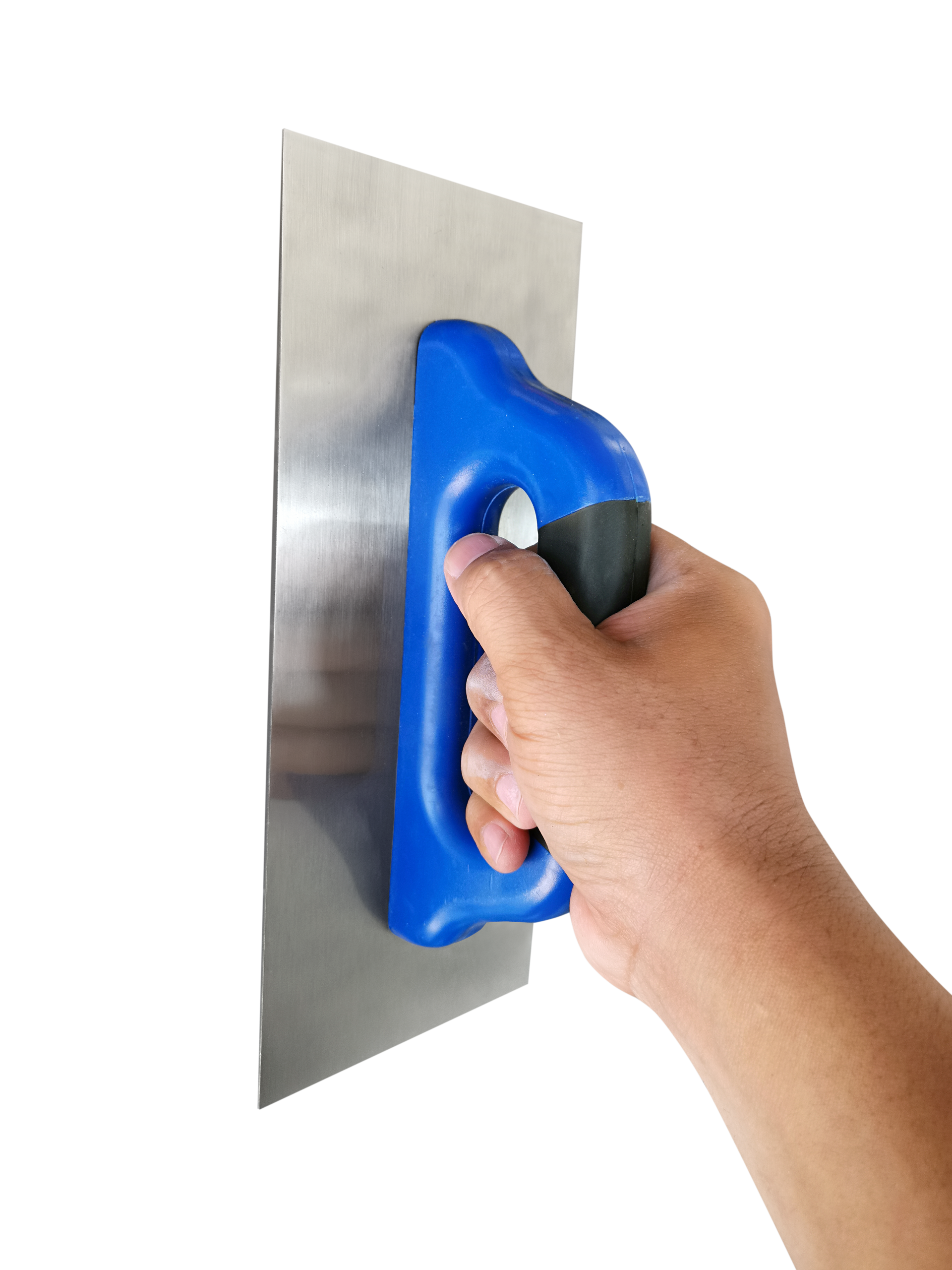 Une main tient une truelle à manche bleu et noir. La truelle est argentée, et un mur blanc se détache en arrière-plan.