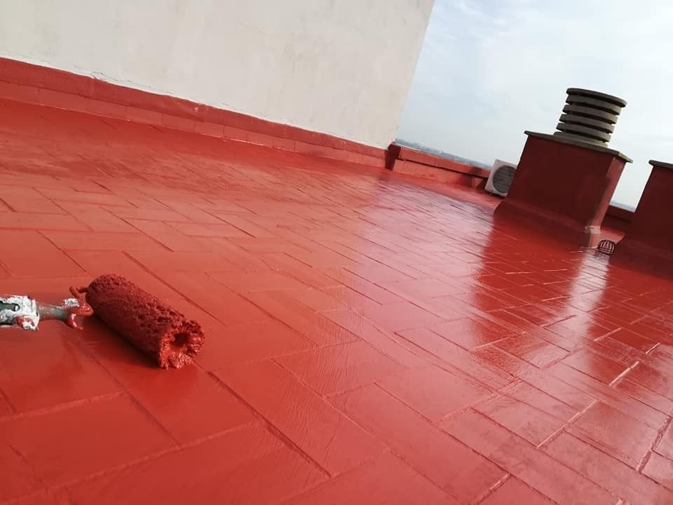 Azotea pintada de rojo con un rodillo y una lata de pintura en el suelo.