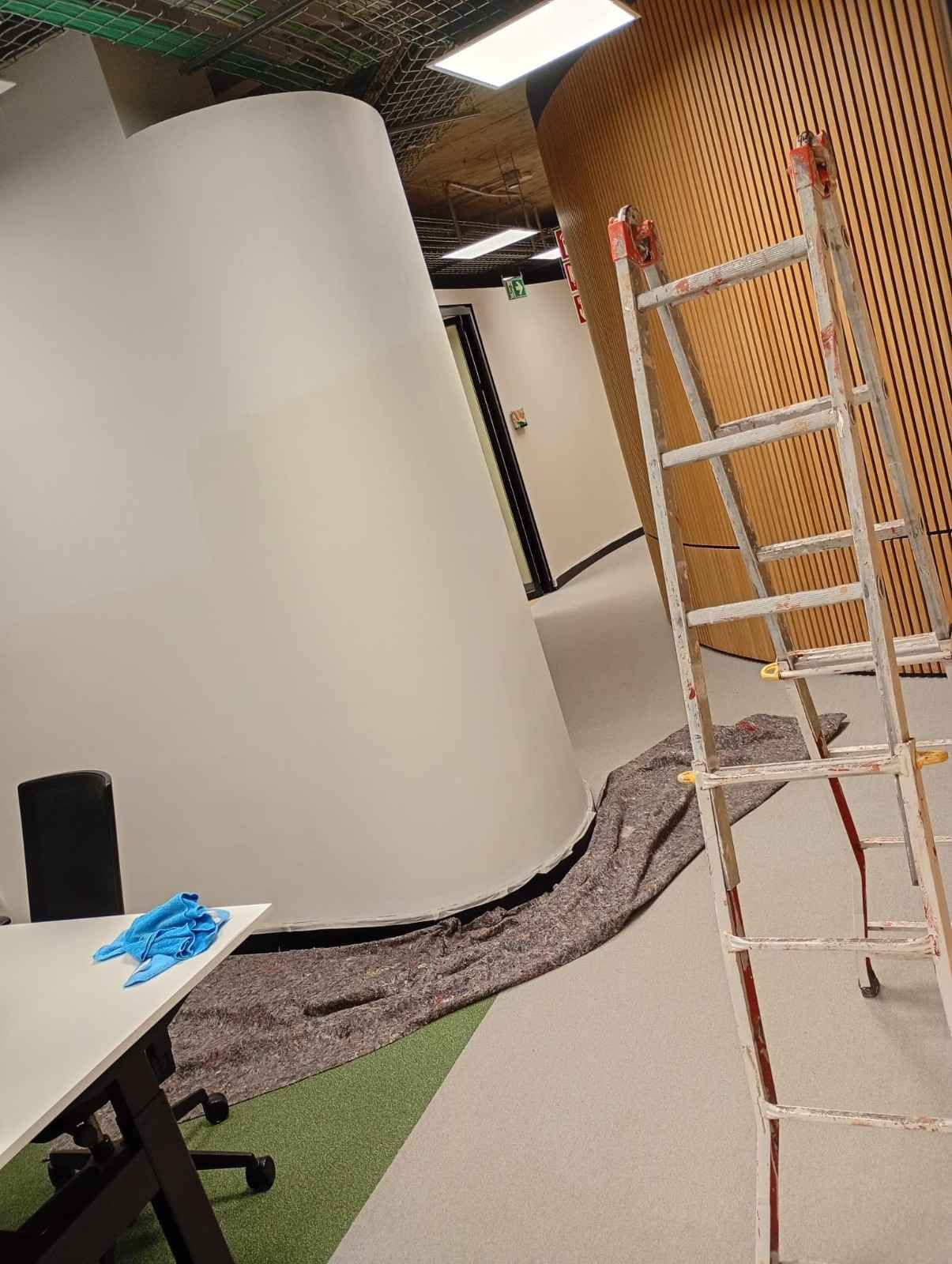 Interior con una gran pared curva blanca, una pared de malla naranja