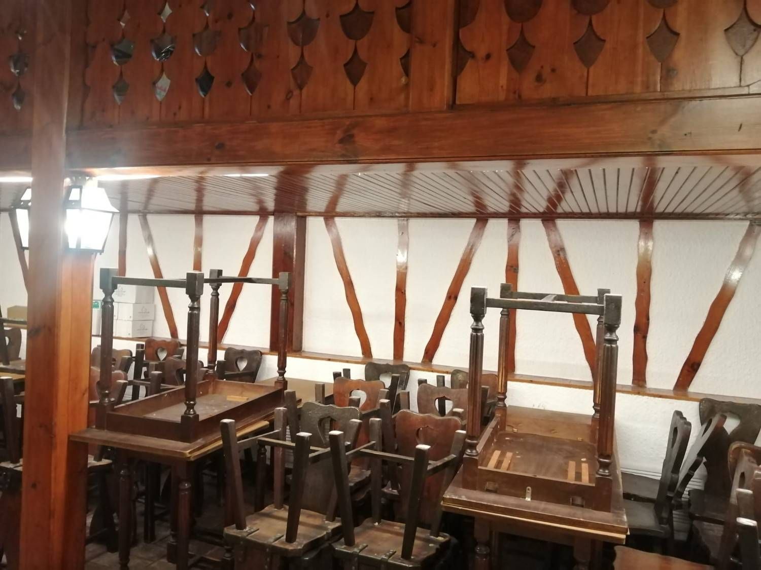 Aula vacía con pupitres y sillas de madera apilados bajo una luz cálida.