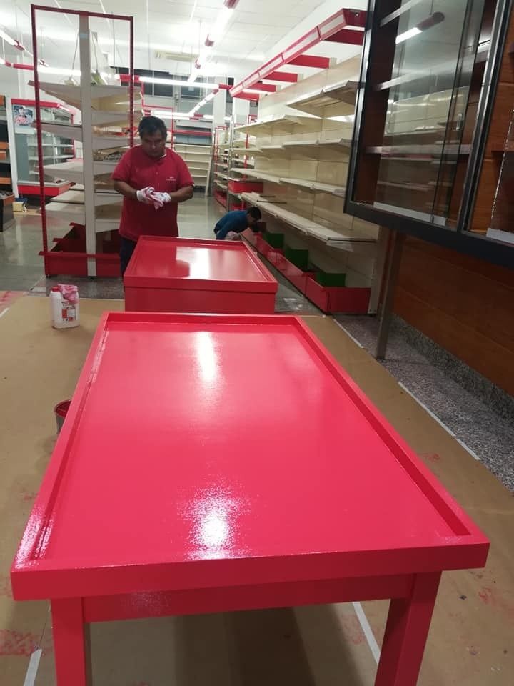 Piscina azul brillante en el patio trasero, junto a un patio con un cubo y herramientas en primer plano.