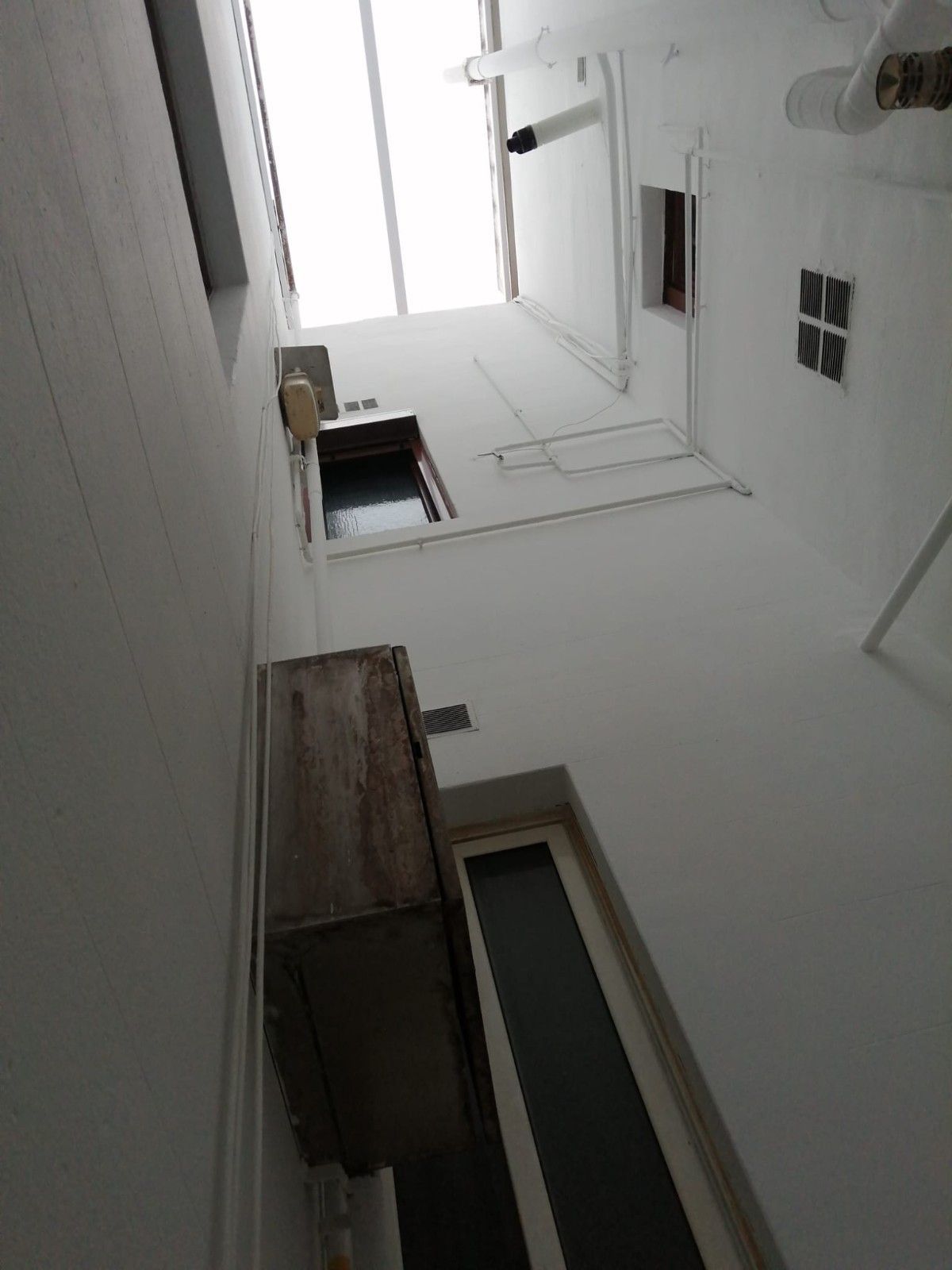 Al mirar hacia arriba, se ve un estrecho patio blanco con ventanas y toldos de madera en el techo.
