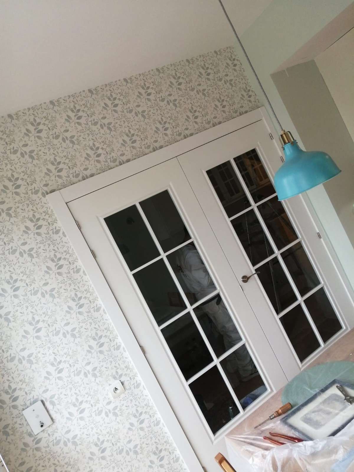 Vista inclinada de una habitación con puertas francesas blancas, papel tapiz 