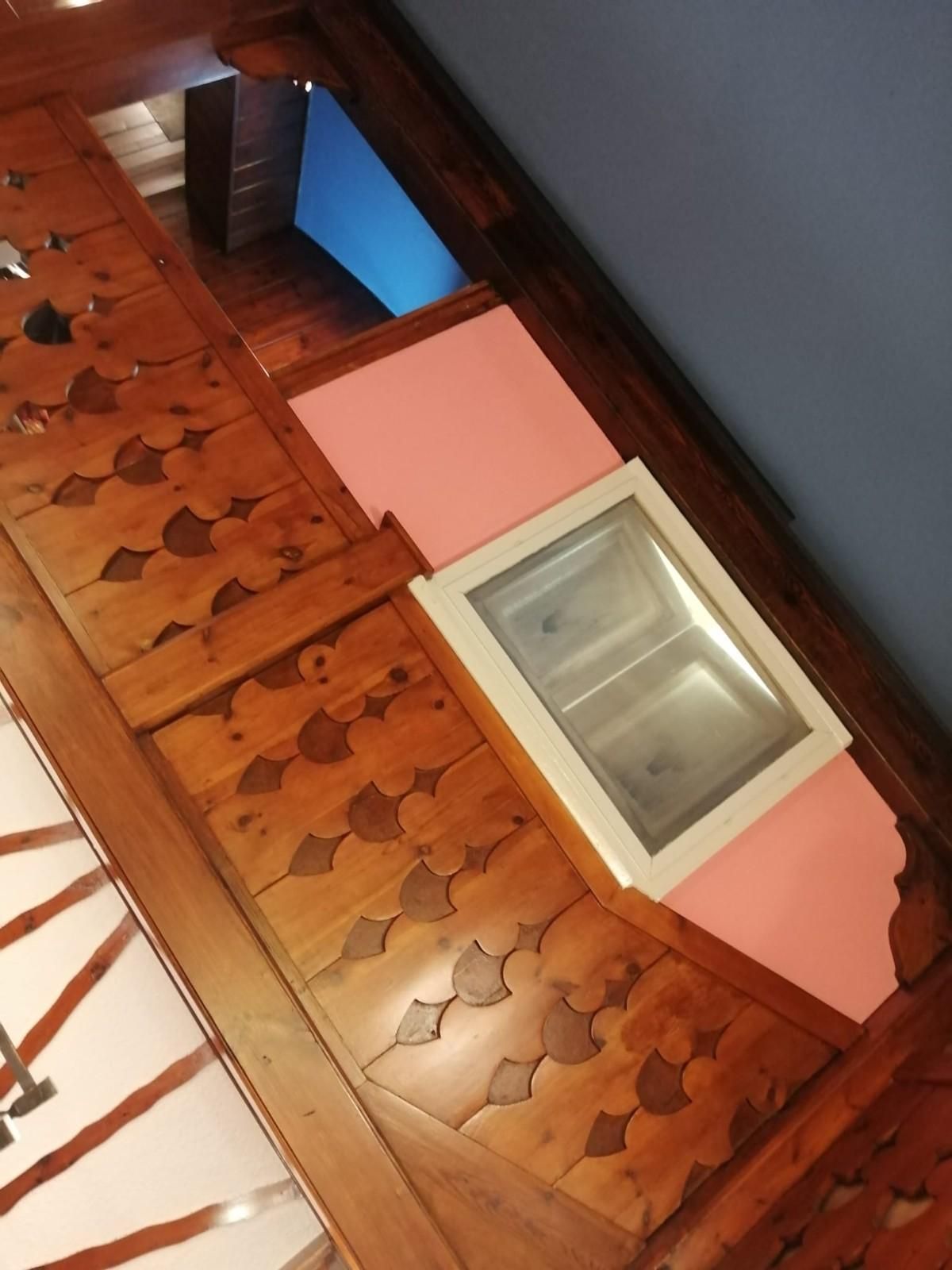 Suelo de madera con esteras de espuma rosas y azules junto a una caja de arena 