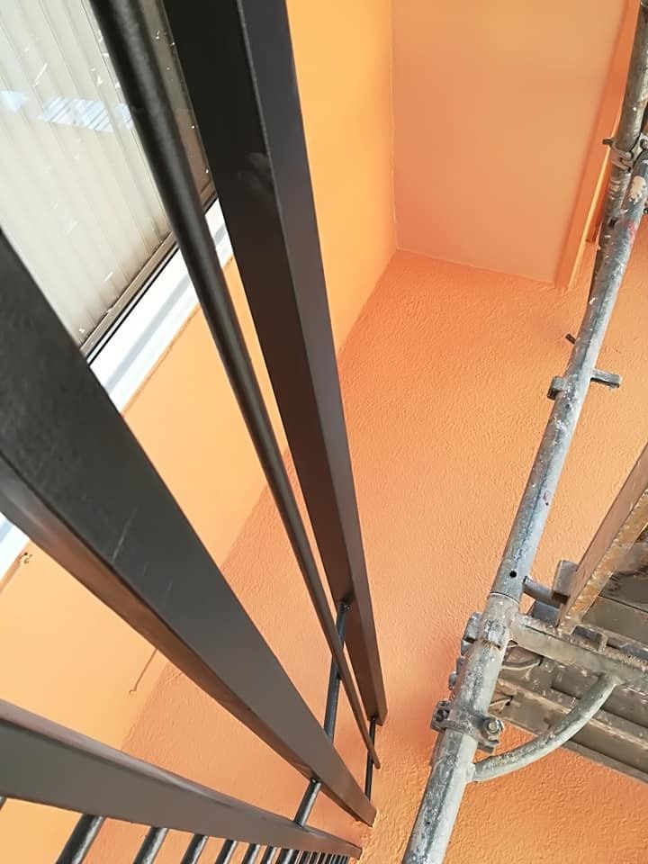 Escalera naranja con barandillas negras y un andamio de construcción a la derecha.