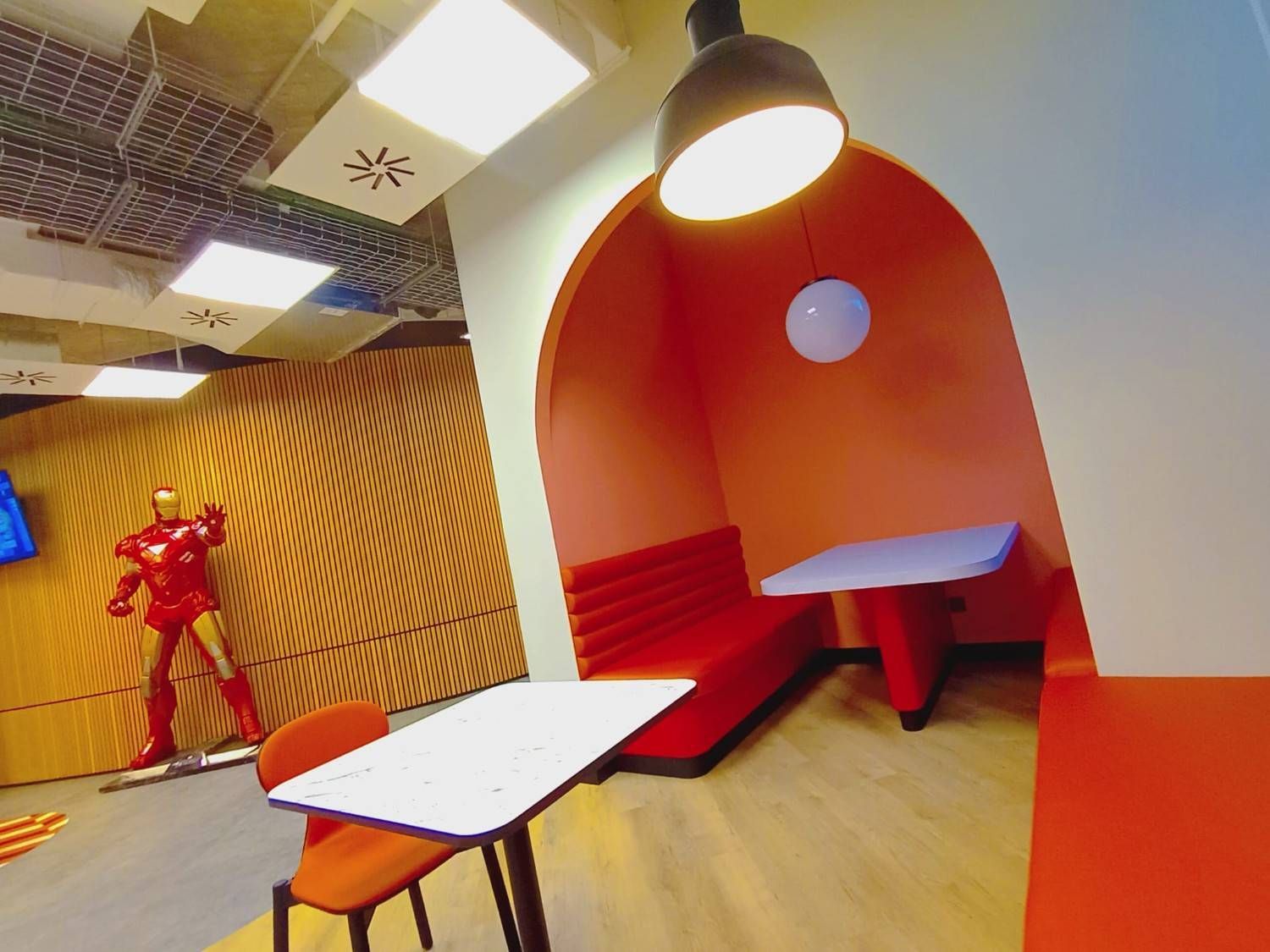 Un trabajador pinta un mural en una pared bajo un andamio, con casco blanco y guantes.