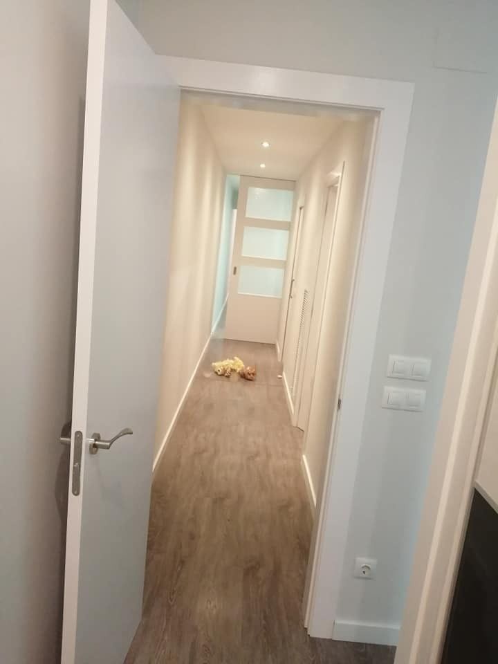 Pasillo con paredes blancas, suelo de madera y un pequeño juguete amarillo en el suelo cerca del fondo.