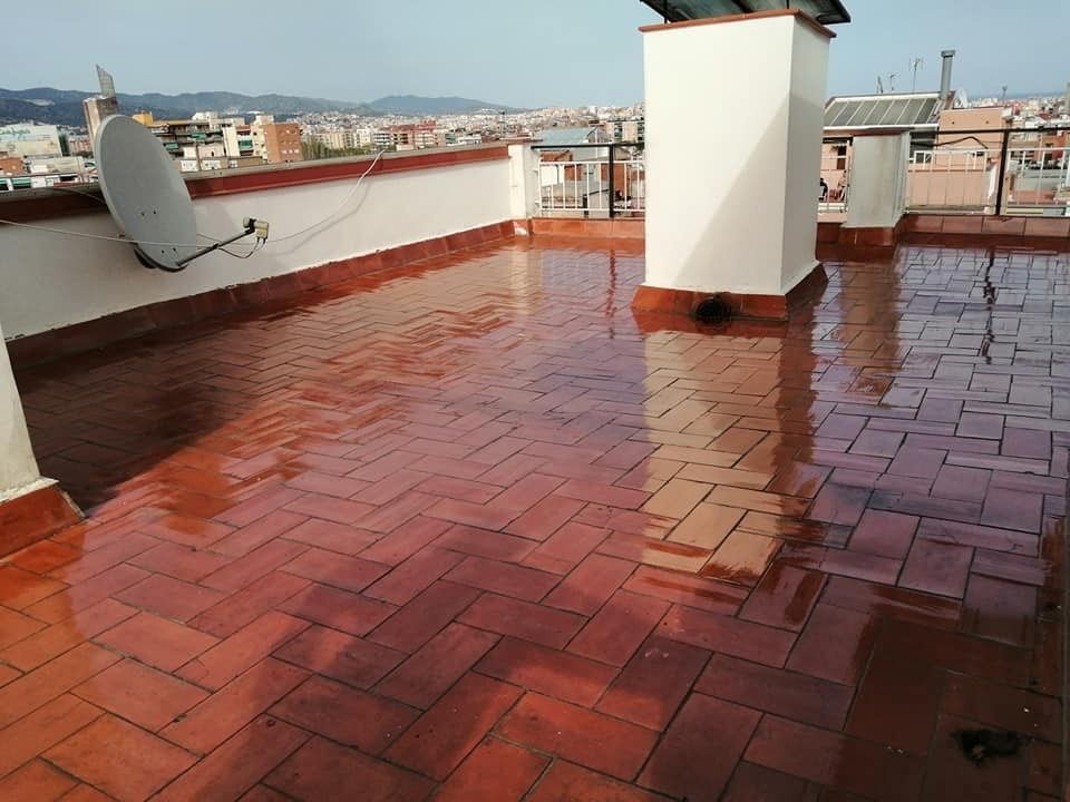 Terraza en la azotea con tejas rojas mojadas, una antena parabólica