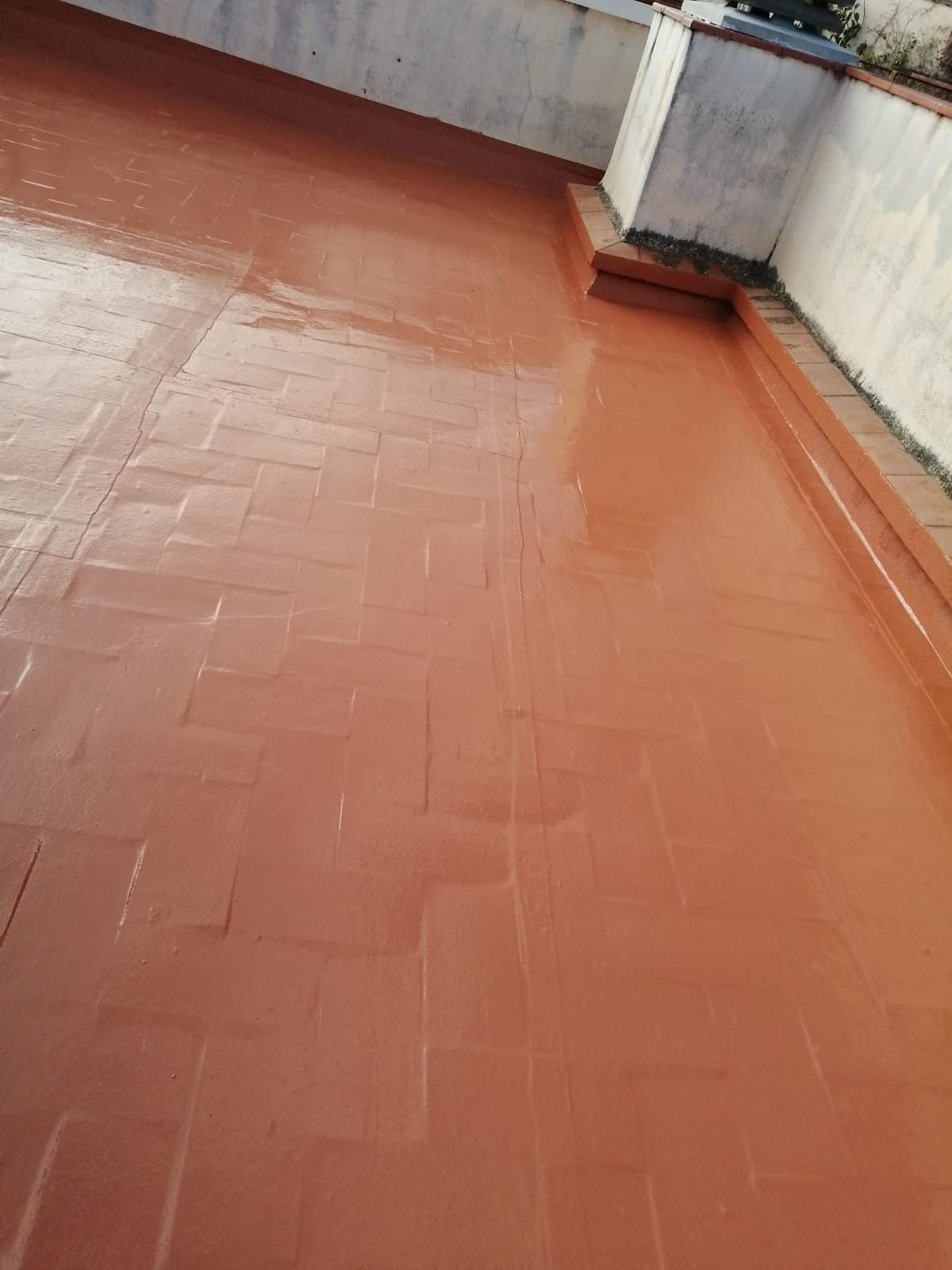 Tejado de tejas rojas con muros de parapeto blancos y una pequeña chimenea o ventilación.