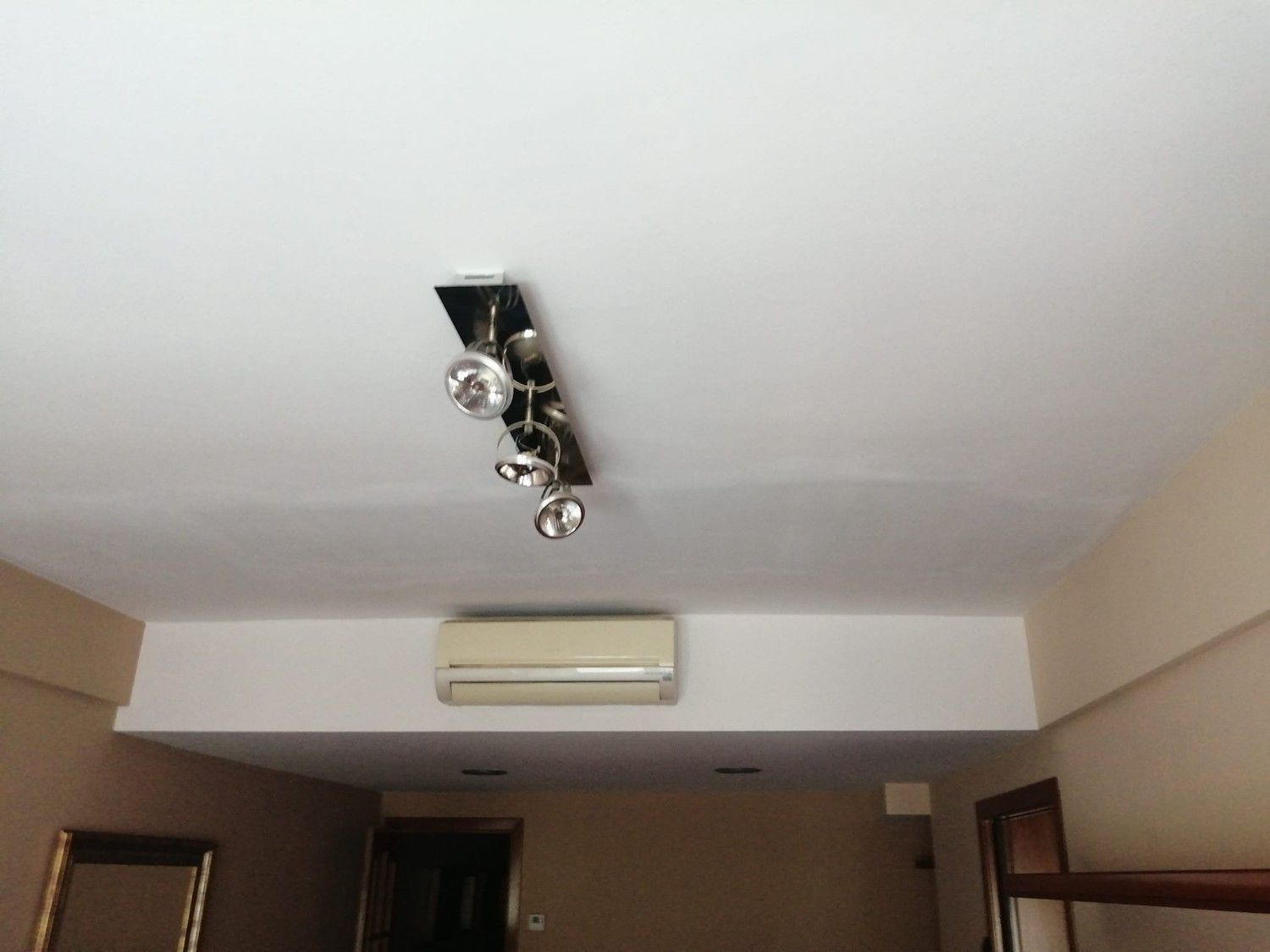 Lámpara de techo y aire acondicionado de pared en una habitación pequeña.