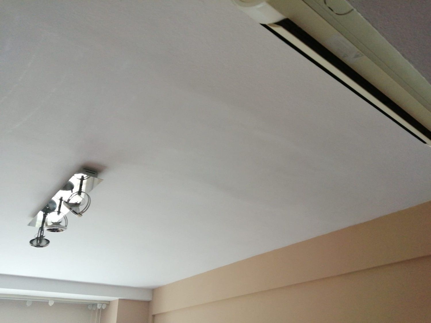 Techo con luminaria empotrada y rejilla de ventilación en una habitación de color beige.