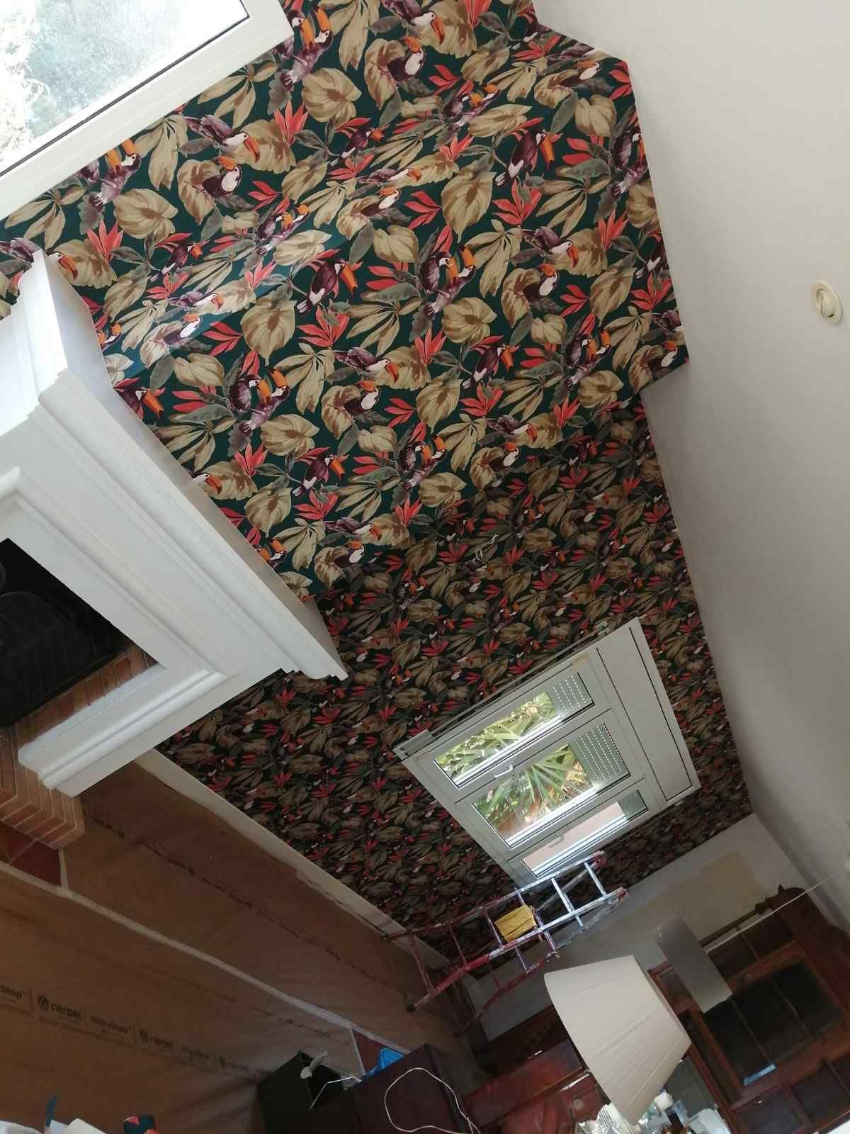 Vista invertida de una habitación con papel pintado floral, ventana, lámpara y suelo de madera.