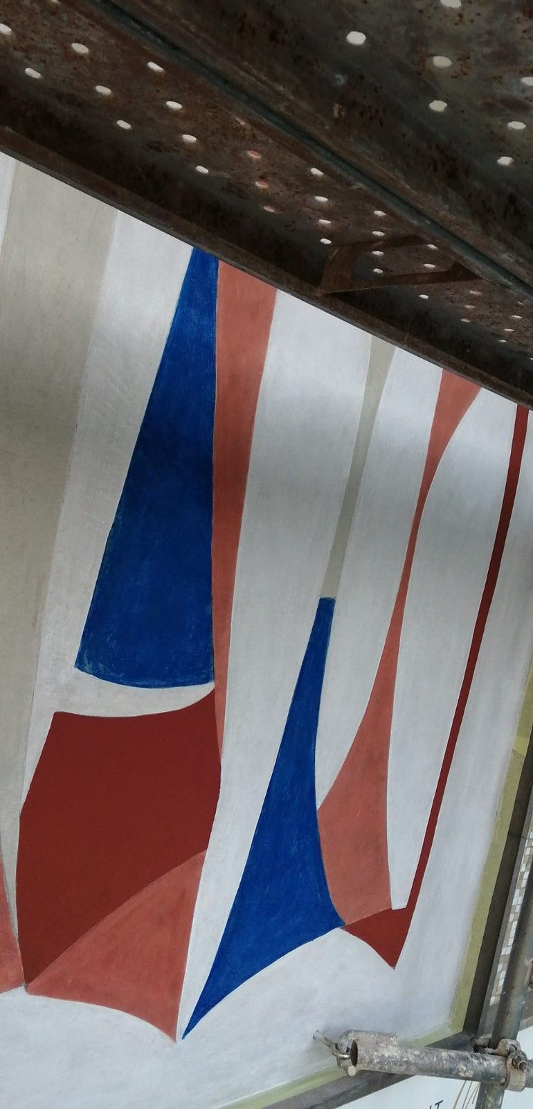 Pancartas de tela rojas, blancas y azules colgando bajo un panel de techo perforado.