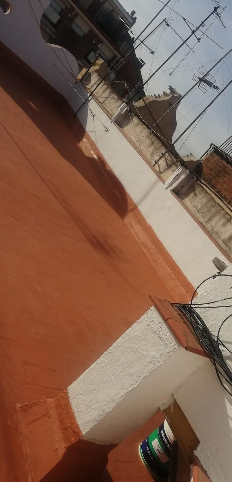 Azotea inclinada con suelo de terracota, paredes blancas y antenas de televisión bajo un cielo despejado.