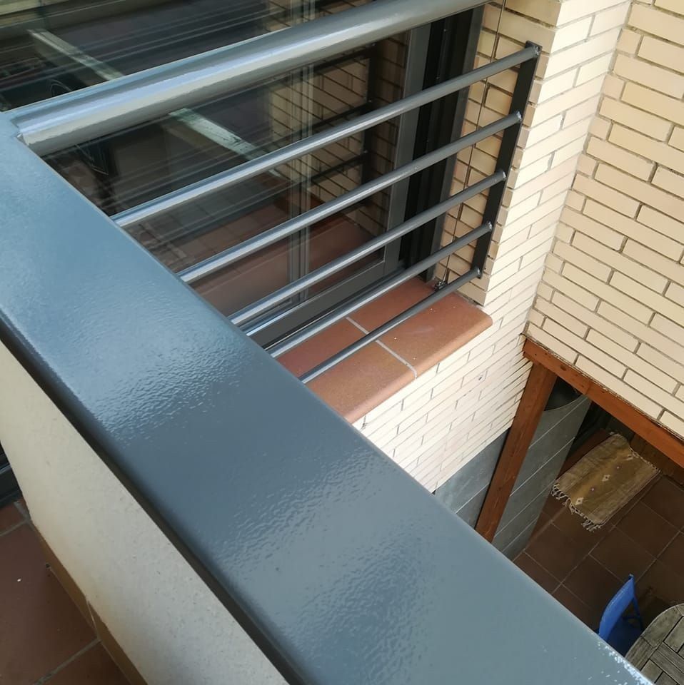 Vista desde un balcón con barandilla metálica con vistas a un patio de ladrillos.