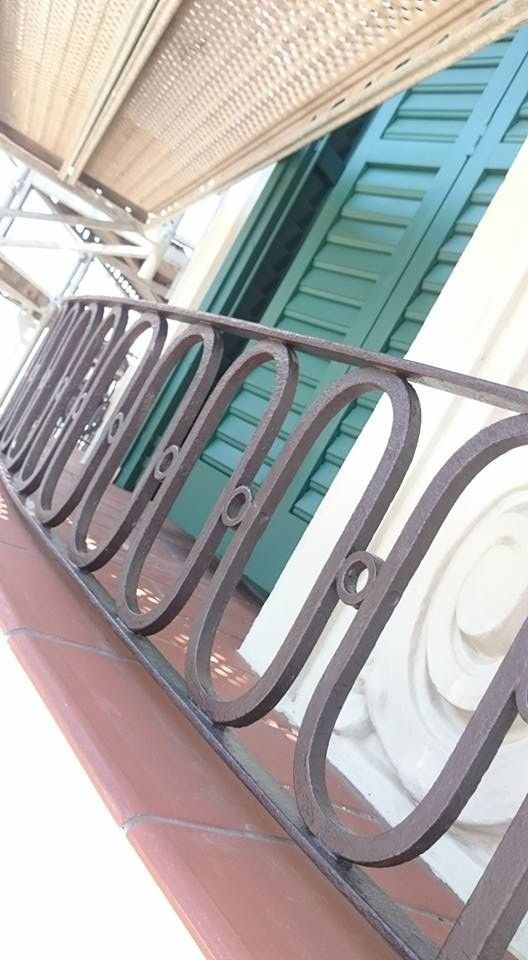 Vista inclinada de una barandilla de balcón con contraventanas de color verde azulado y un techo tejido.