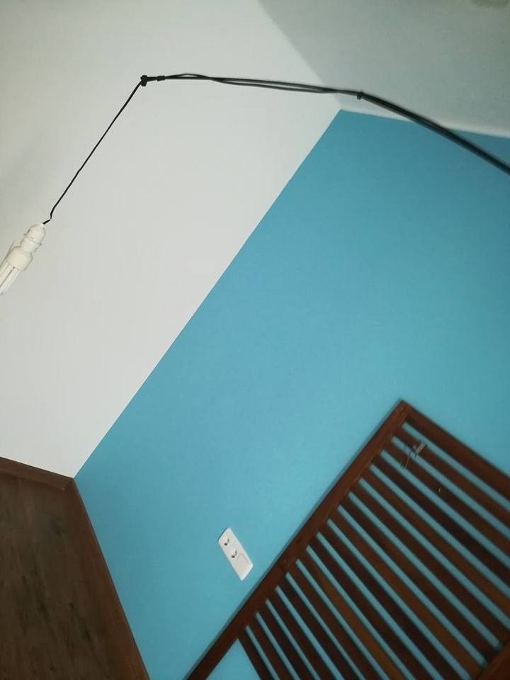 Vista inclinada de la esquina de una habitación con paredes azules y blancas y un cabecero de madera oscura.