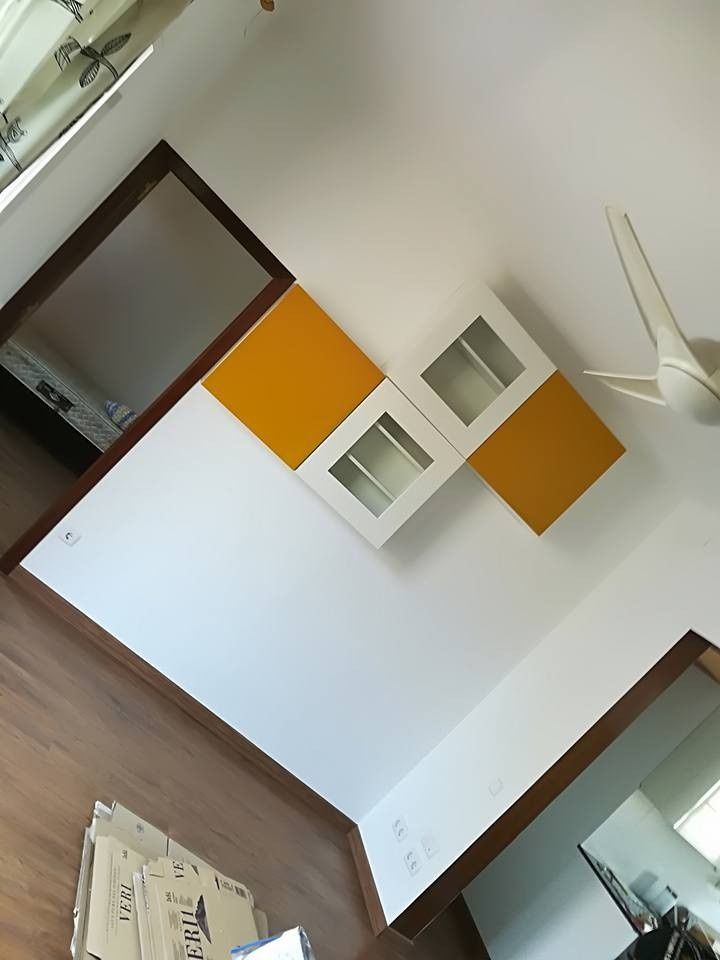 Habitación vacía con paredes blancas, suelo de madera, paneles de pared naranjas y un ventilador de techo.