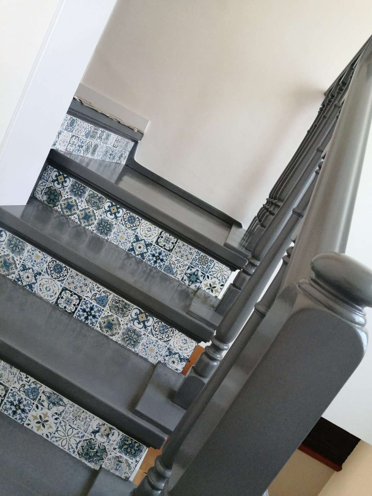 Escalera con alfombra gris, escalones estampados y barandilla gris oscuro en el interior de una vivienda.
