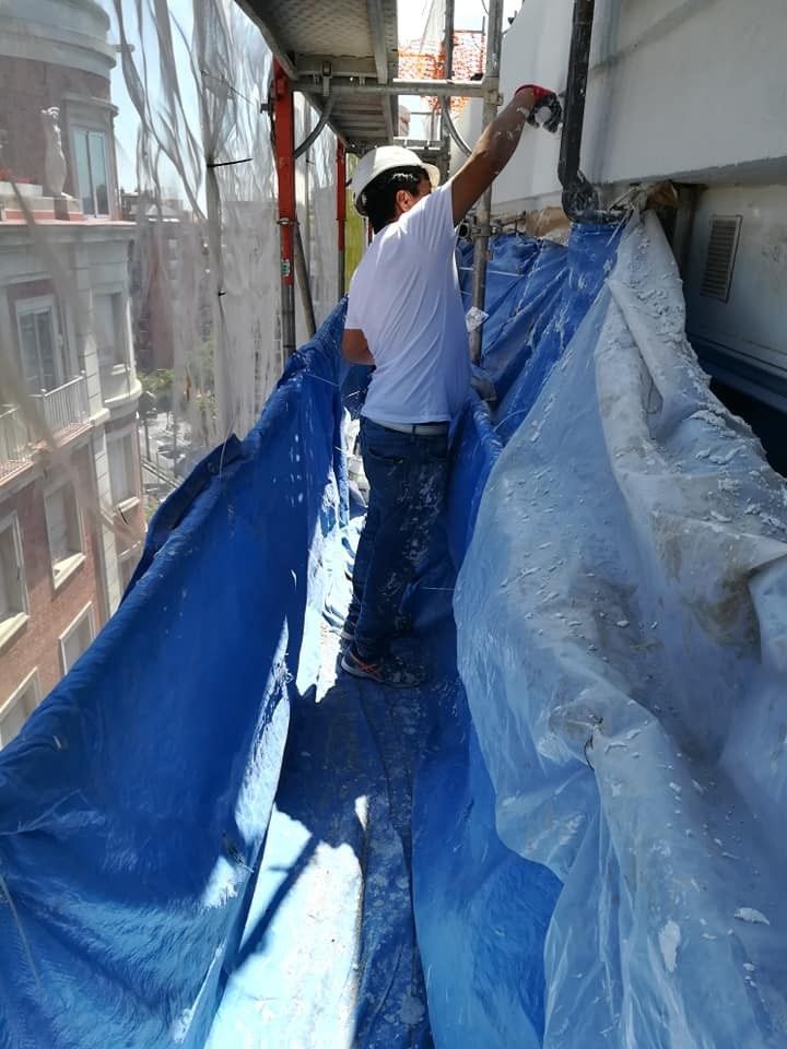 Un obrero pinta la fachada de un edificio desde la ventana de un rascacielos