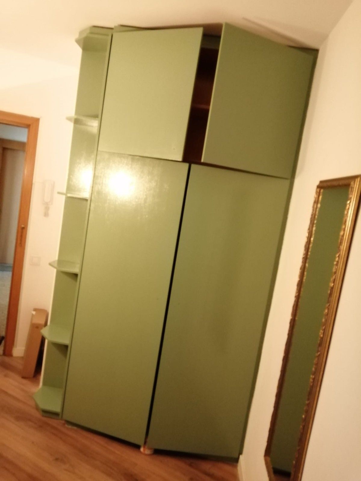 Armario verde en un pasillo con puerta superior abierta y suelo de madera.